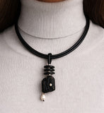 Necklace with a black pendant and pearl on a white turtleneck