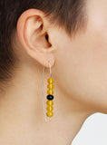 Earring with yellow natural Amber beads and a silver hoop worn by a person.