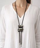 Necklace with a unique  leather black with gold and silver pendant on a white top