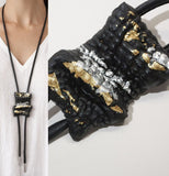 Black leather necklace with gold and silver accents worn by a person.