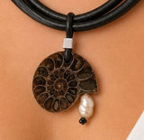 Necklace with a fossil pendant and pearl on a person's neck
