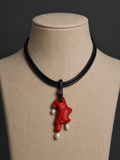 Necklace with a red coral pendant and pearls on a mannequin bust against a dark background
